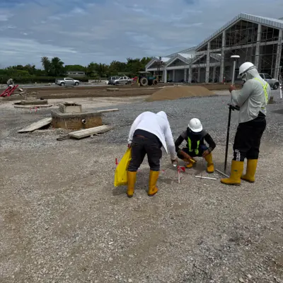 Tiga pekerja berbut kuning menanda titik di tapak pembinaan bangunan yang sedang didirikan.