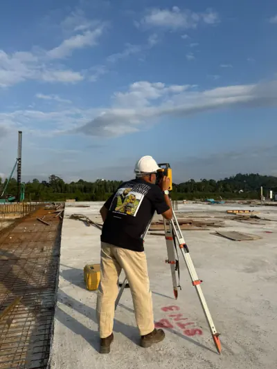 Seorang anggota pasukan berbaju Abe Ukur Tanah mengendalikan total station di atas lantai konkrit bangunan.